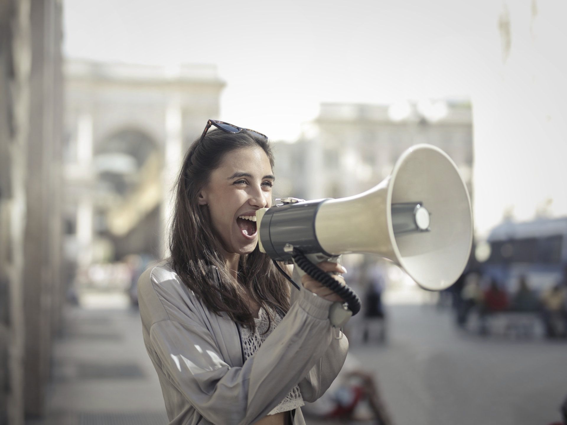 Lady with dark hair holding a megaphone in a city