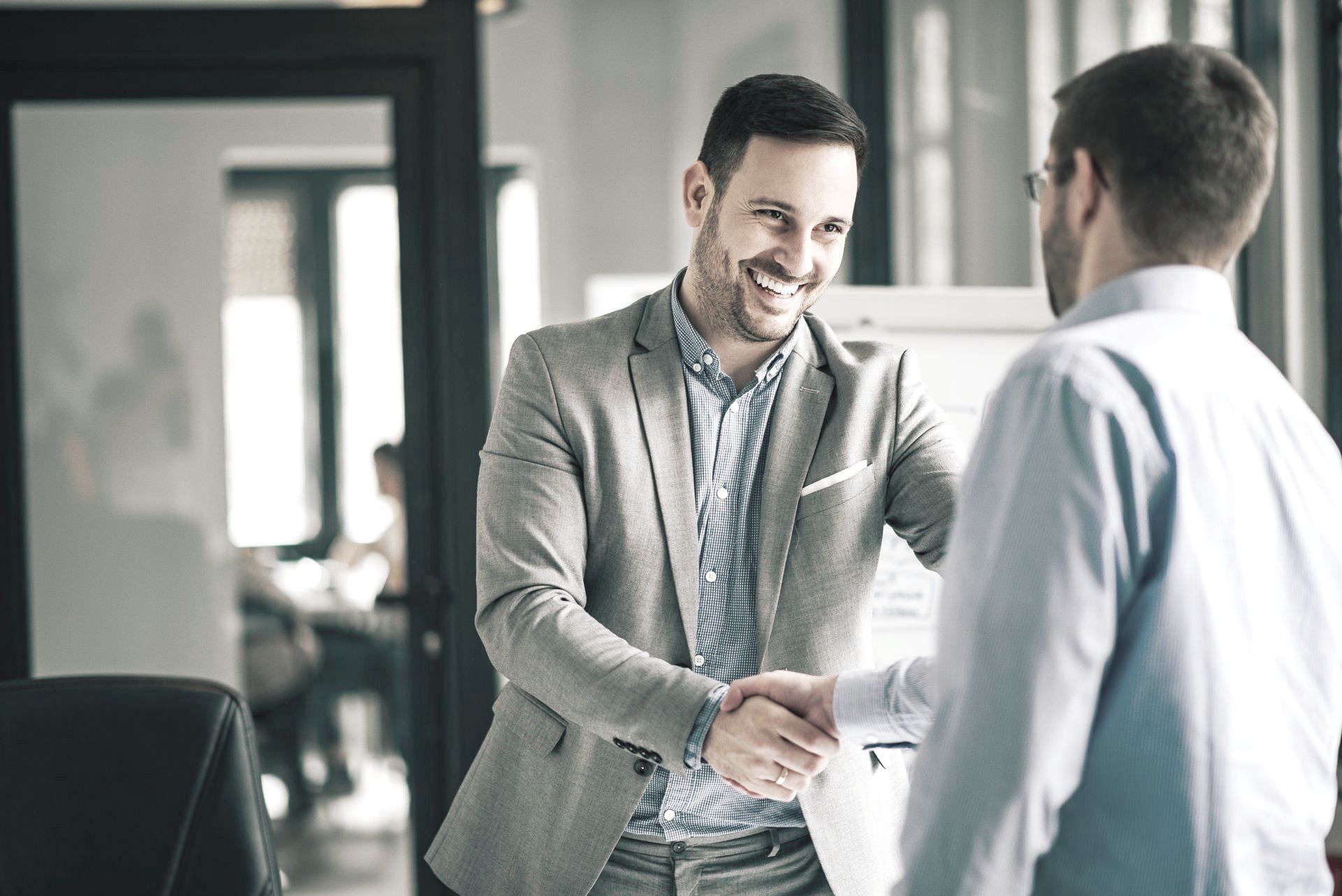 Two men are shaking hands in an office.