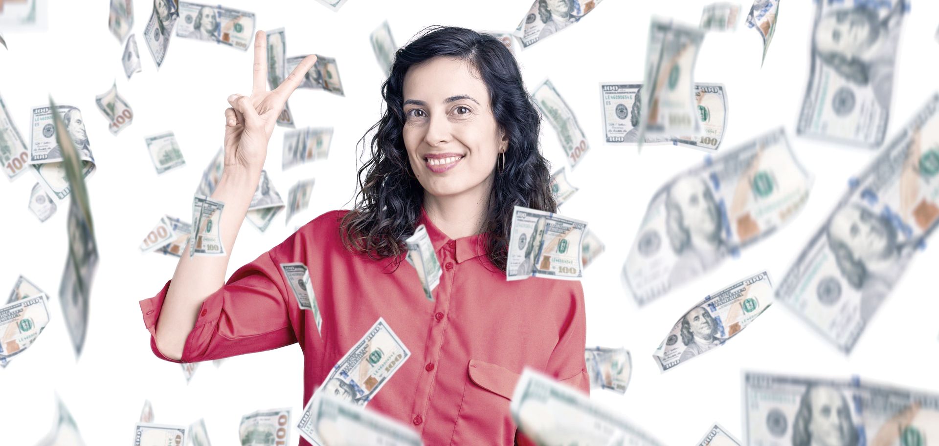 A woman is standing under a rain of money and making a peace sign.