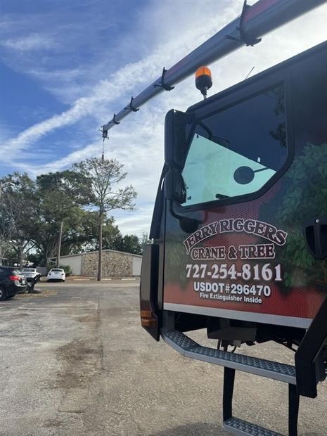 Tree service truck with orange bucket lift parked in a lot, company logo and phone number on the door