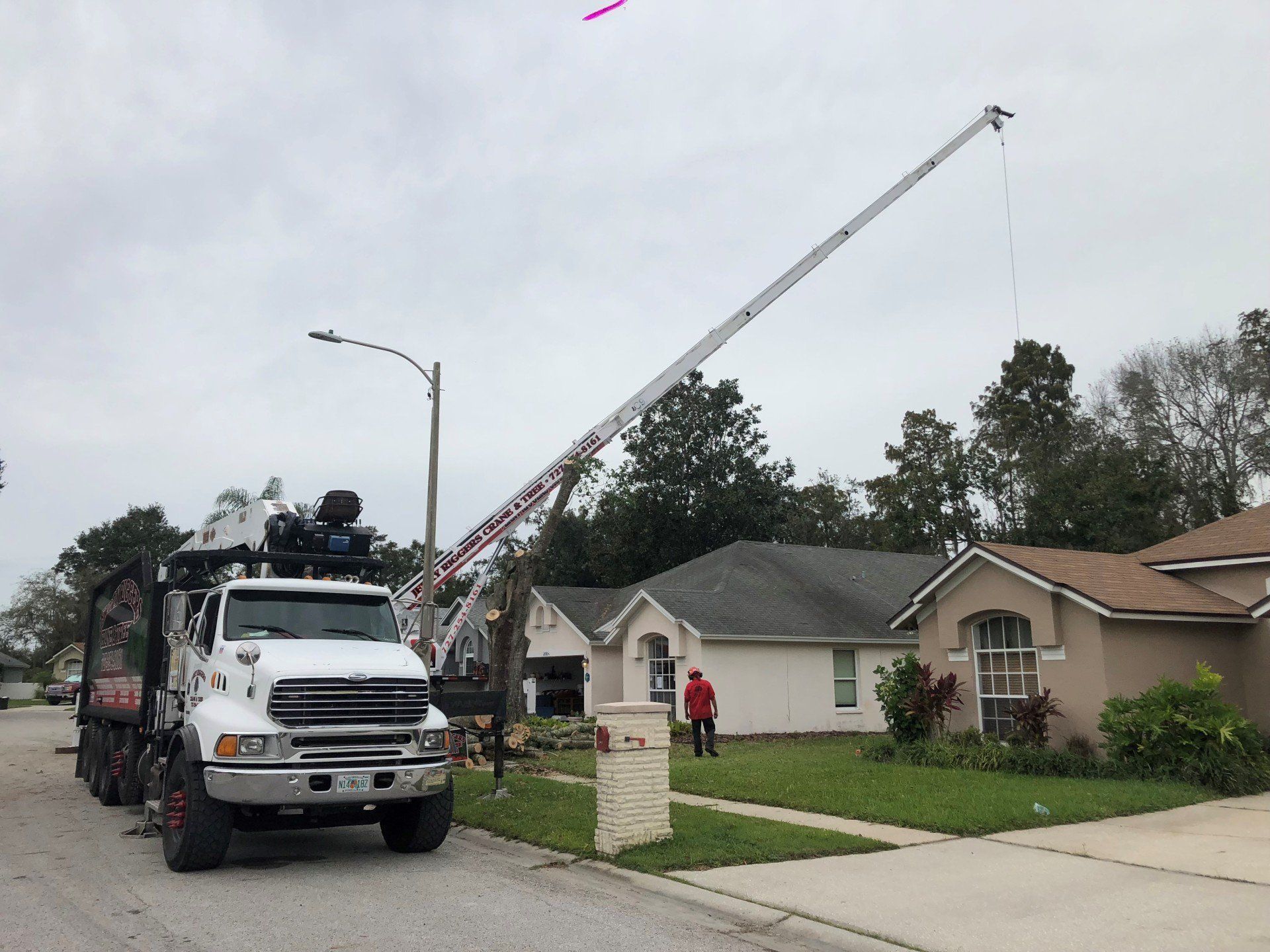 Fire truck with extended ladder parked on a suburban street near a house