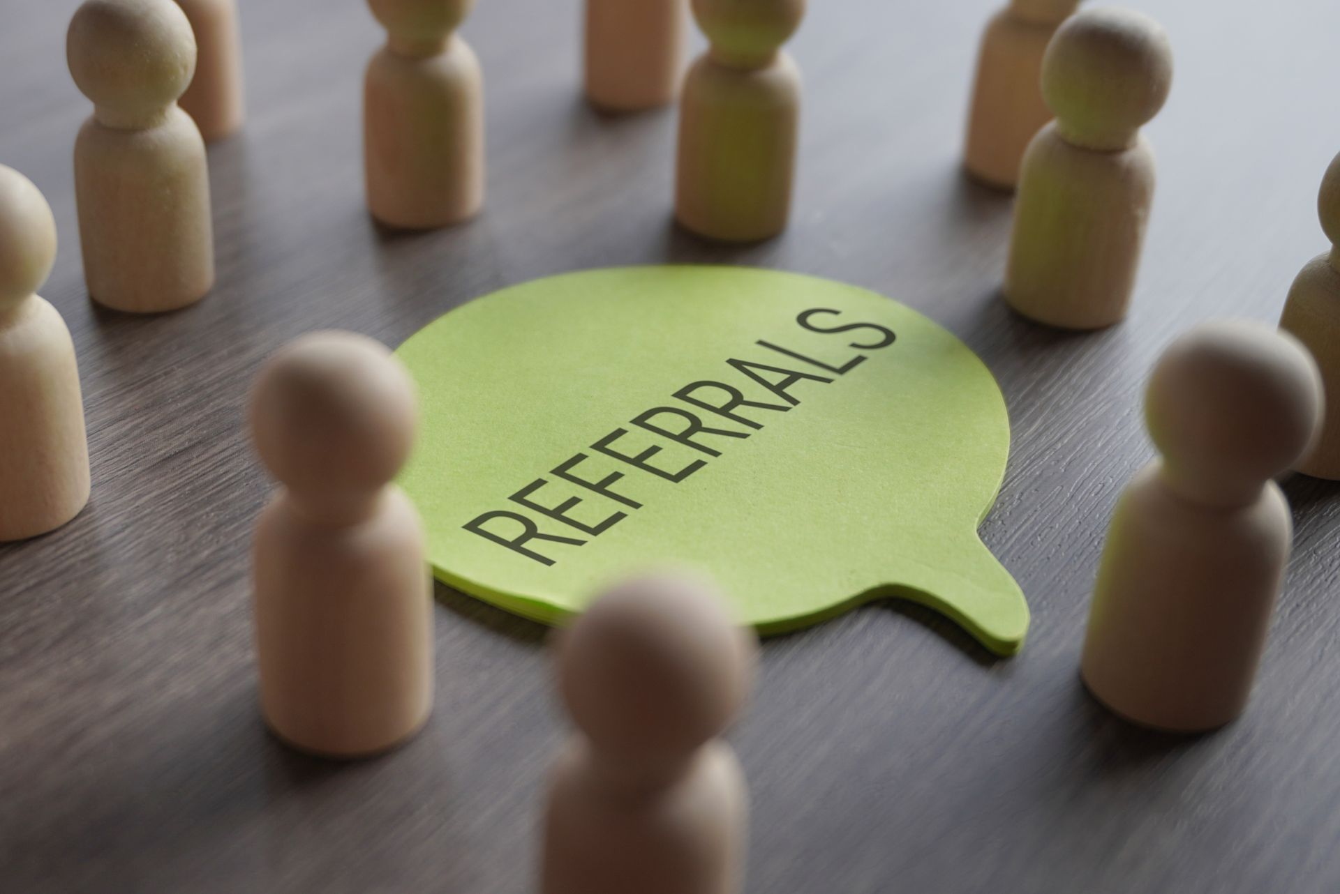 Wooden figures surround a green speech bubble with the word 