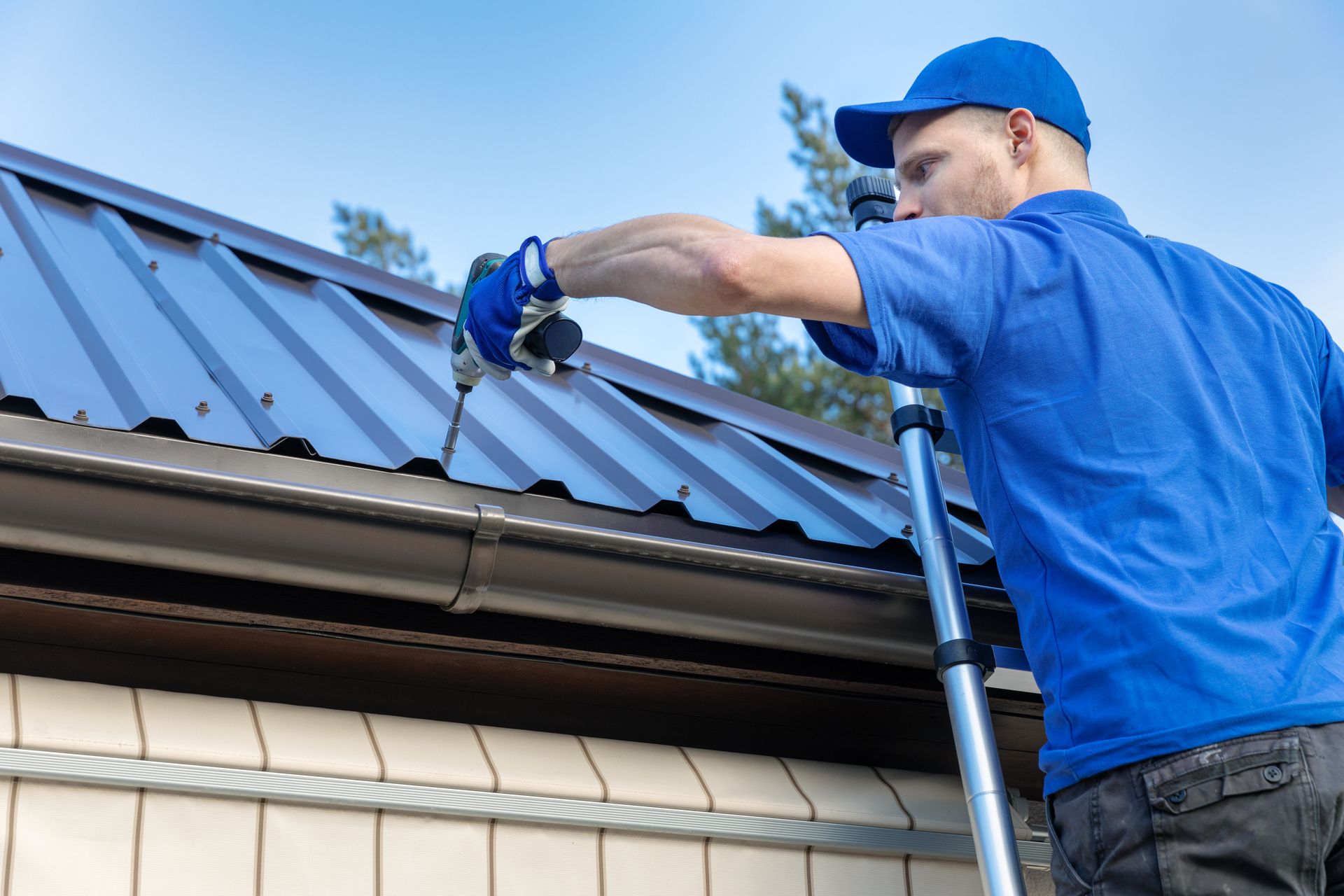 A uniformed roofer from a roofing company is installing a metal roof on a house.