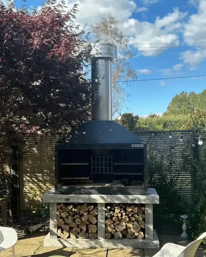A large grill with a chimney on top of it in a backyard.