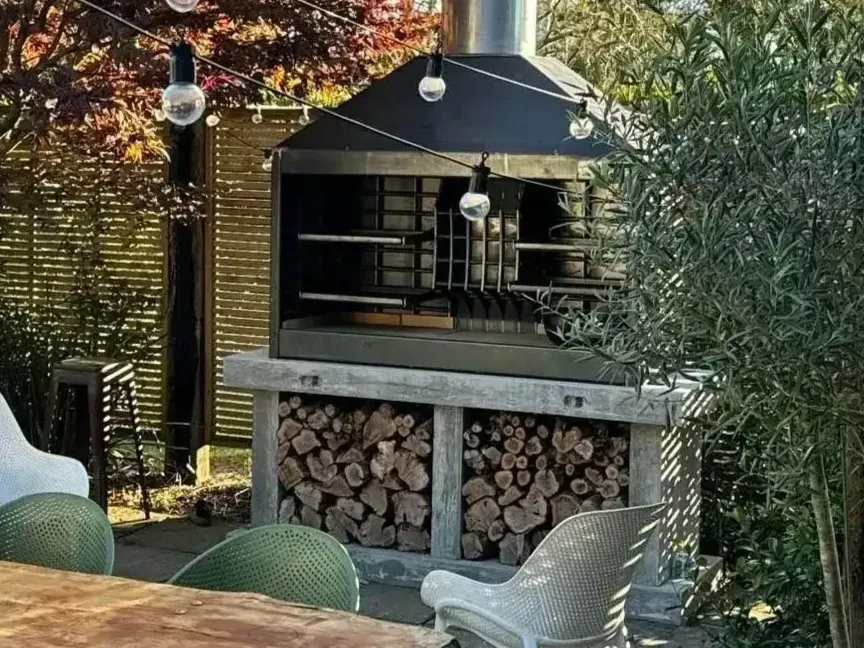 A patio with a grill and a table and chairs