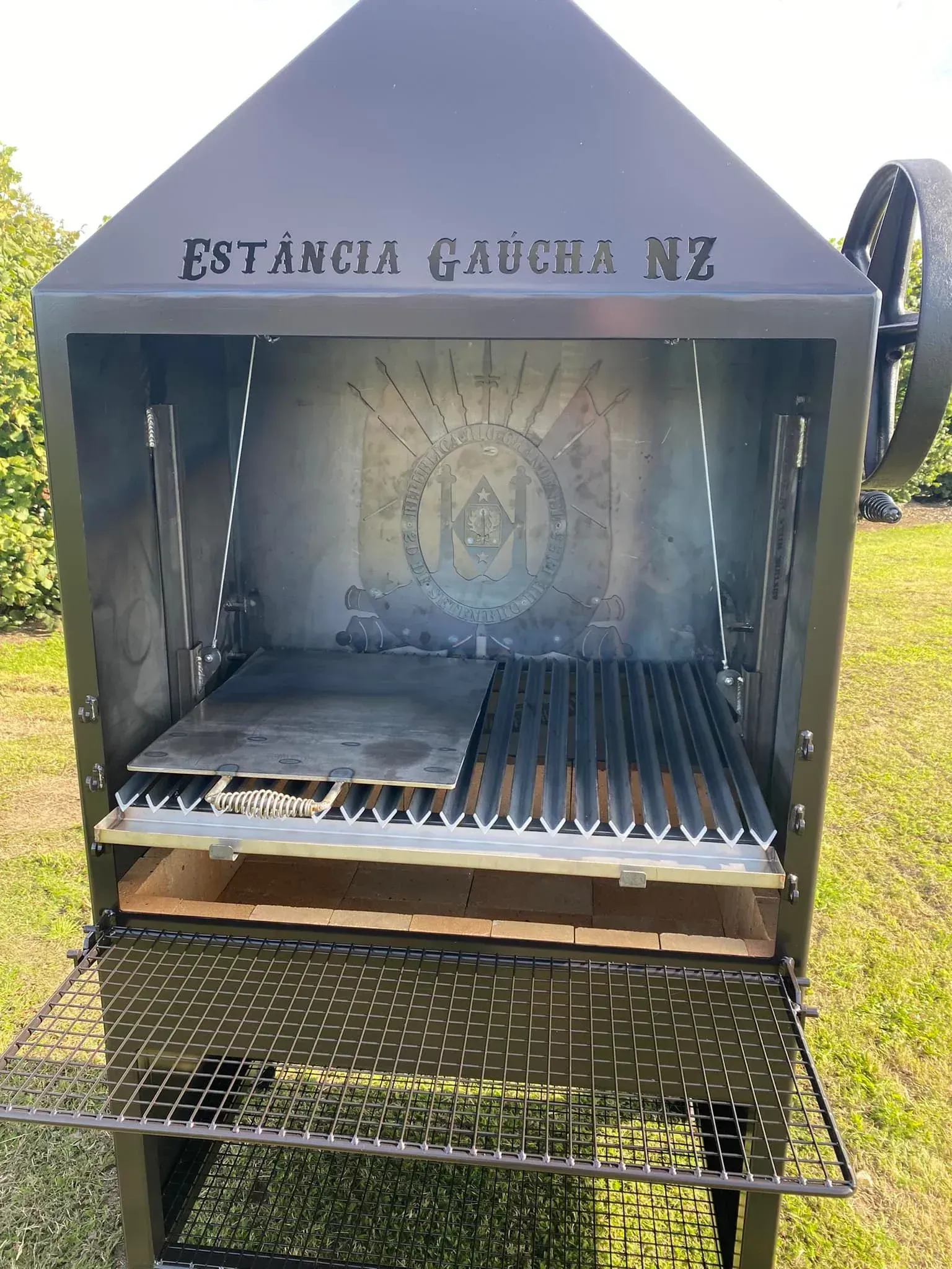A large grill is sitting on top of a lush green field.