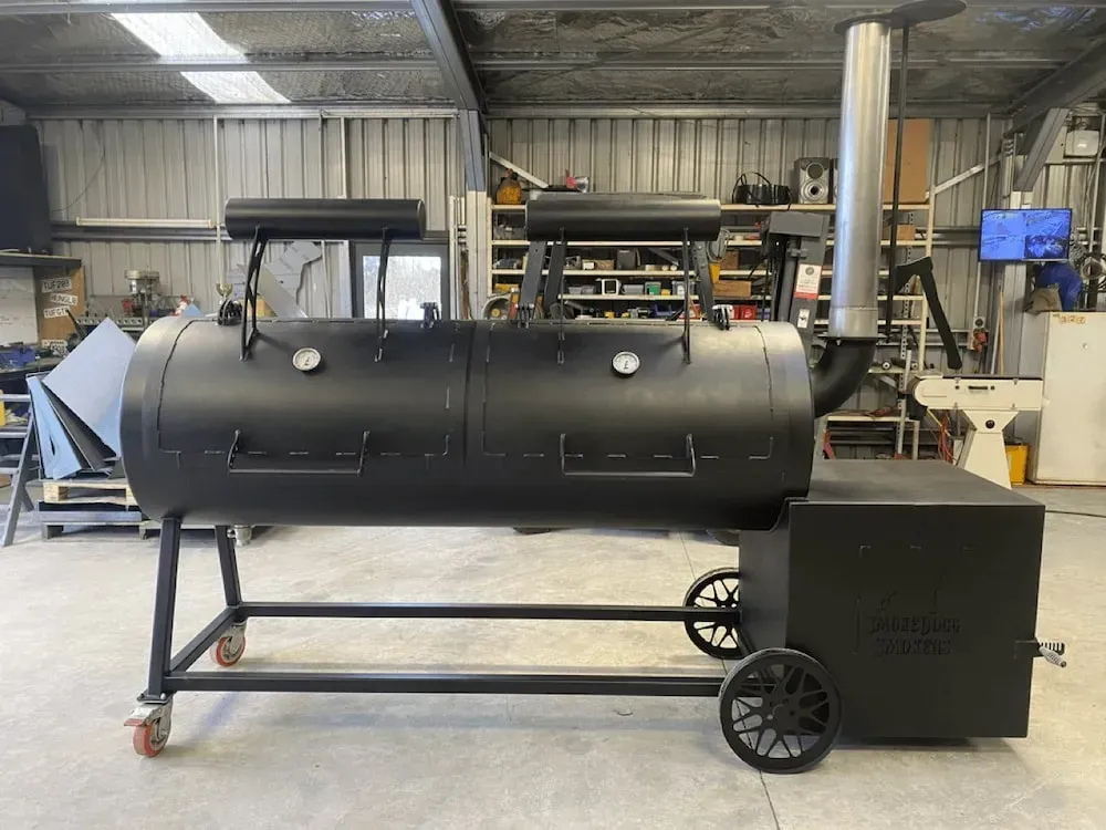 A large black bbq grill is sitting in a garage.
