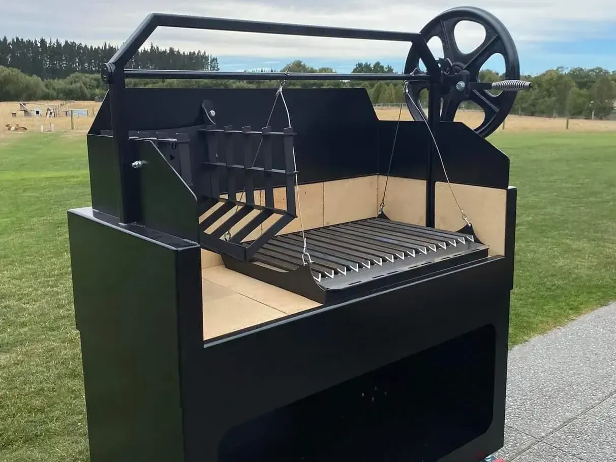 A black grill is sitting on the side of a road in a field.