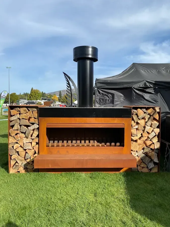 A large fireplace surrounded by logs in a grassy field.