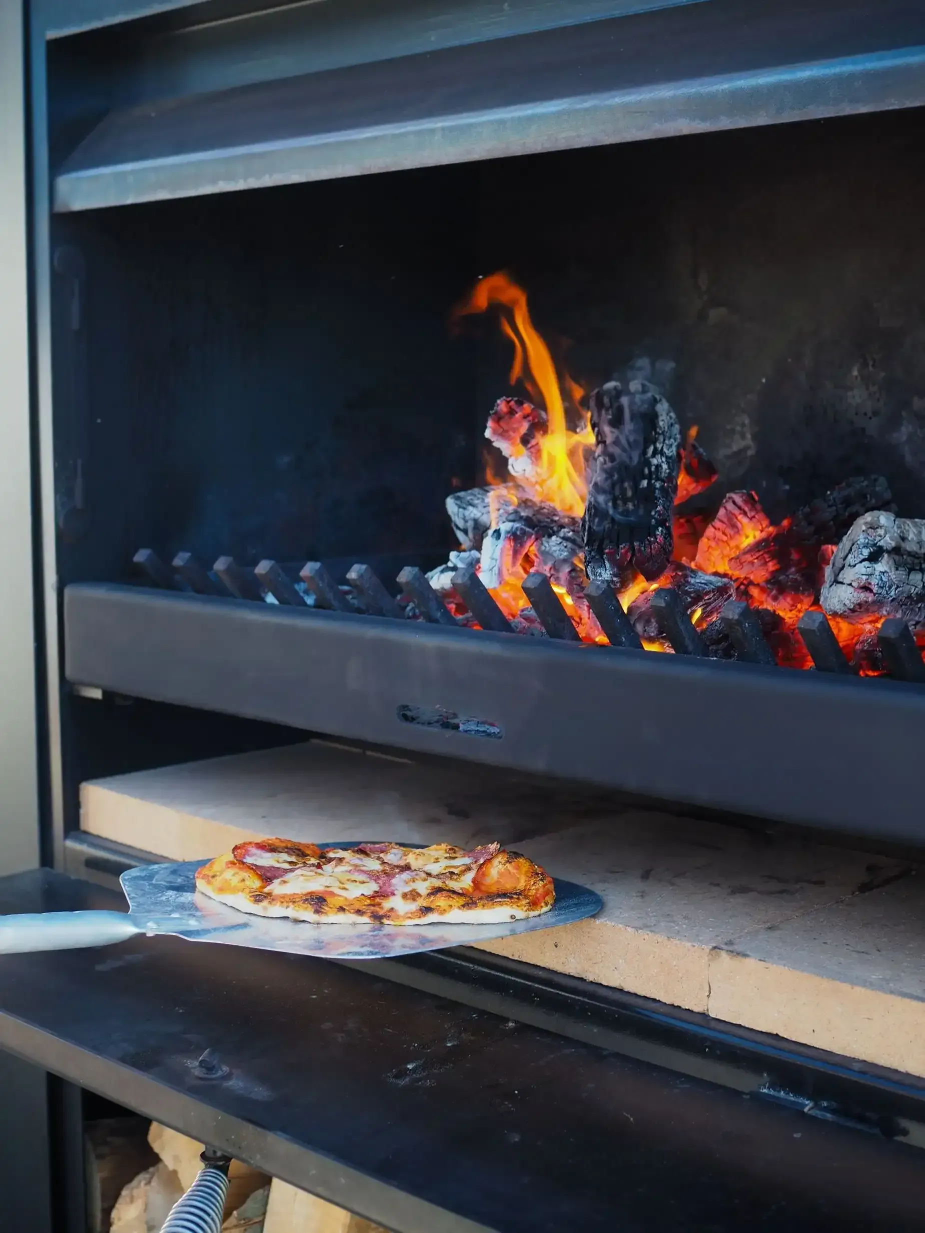 A pizza is being taken out of an oven with a spatula.