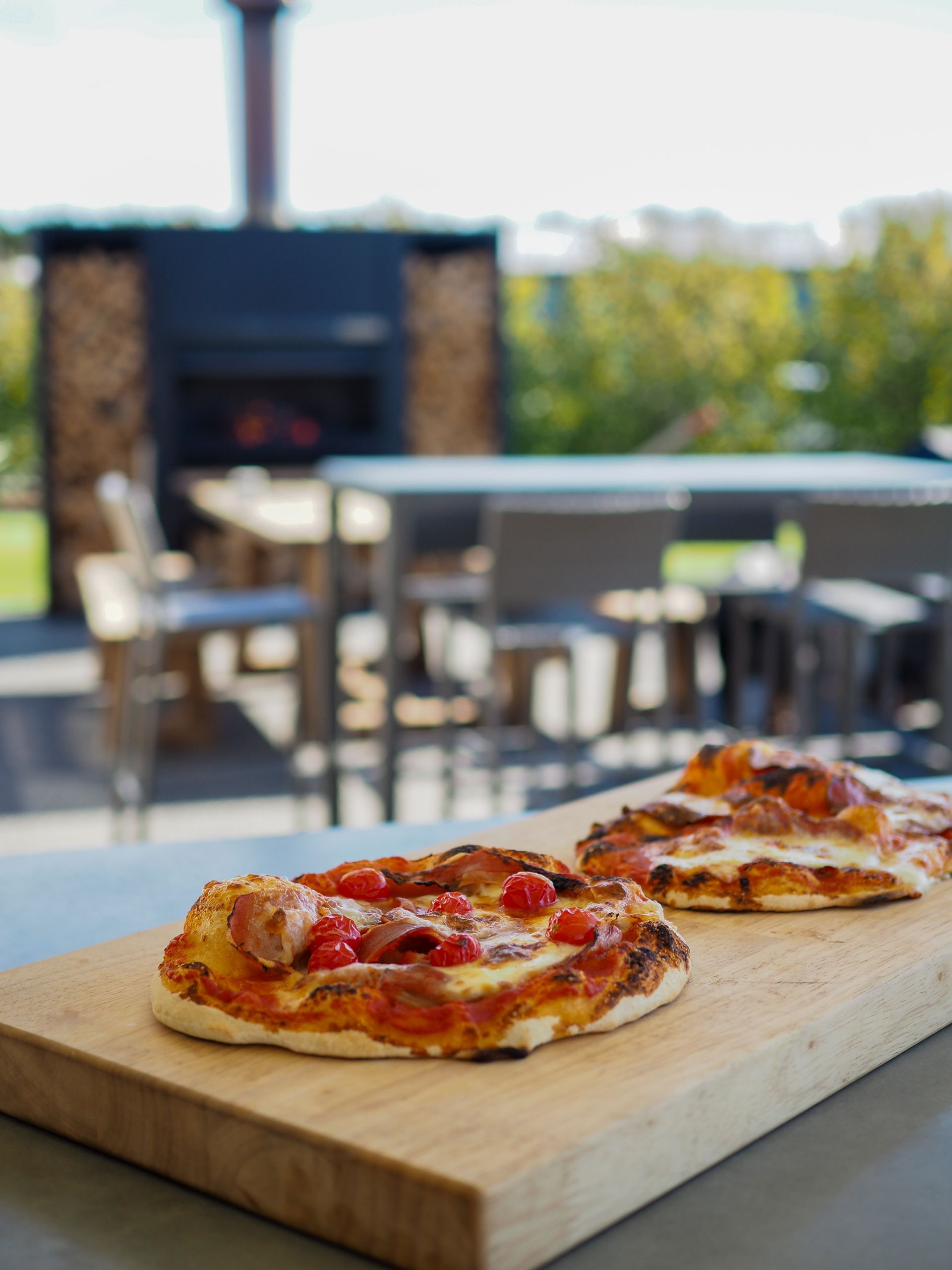 Three pizzas are sitting on a wooden cutting board.