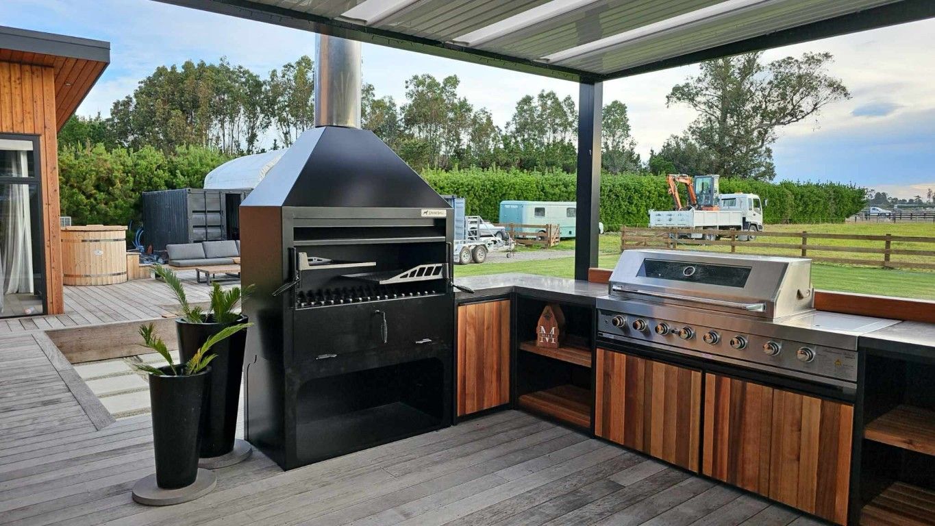 A large outdoor kitchen with a grill and potted plants.