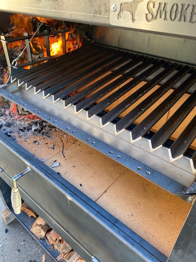 Close-up view of a wood-fired smoker grill with a hot fire burning inside.