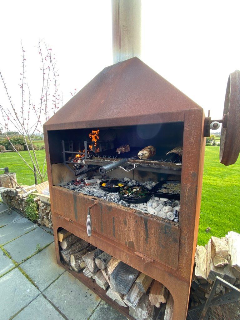 A rusty grill is being used to cook food on a patio.
