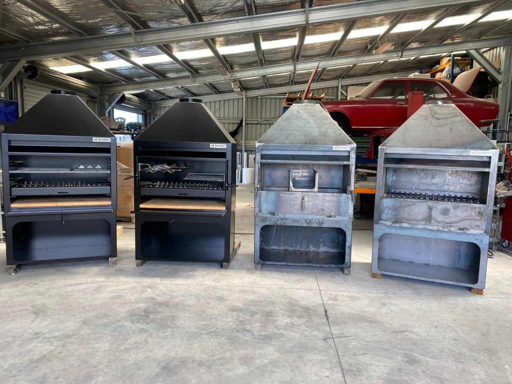 A row of grills are lined up in a warehouse.