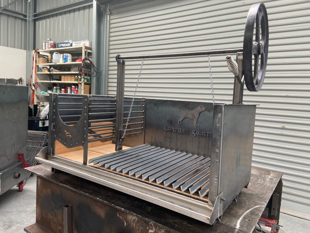 A stainless steel grill with a wheel attached to it is sitting on a table.