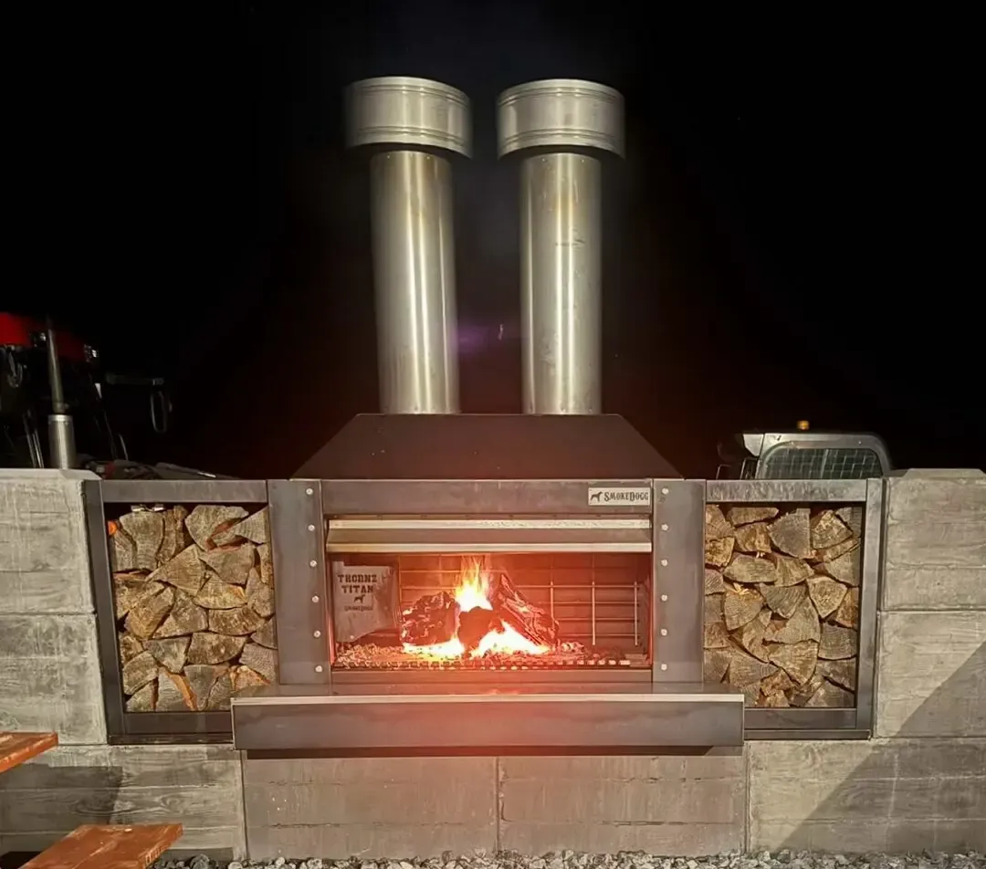 A fireplace with two chimneys and a pile of wood in front of it.