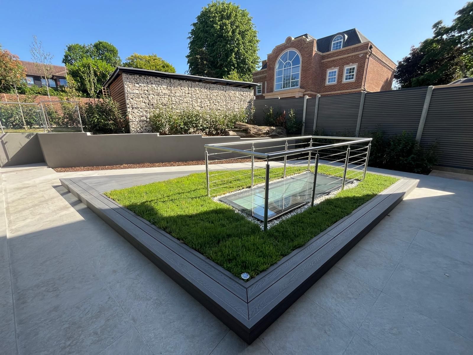 Completed contemporary patio with glass balustrade and landscaping