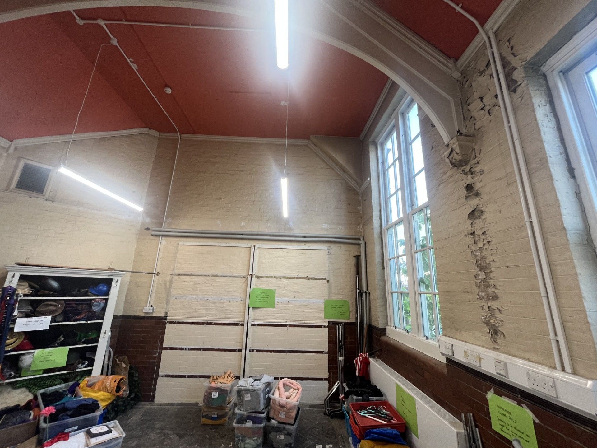 Interior of a school hall before damp proofing works by i2i Contractors, showing damp-damaged walls and storage