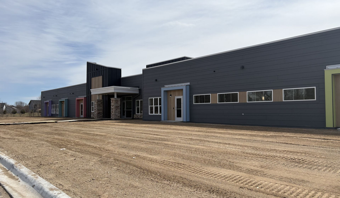 New gray commercial building along a final grade gravel lot under a cloudy sky in Waverly, MN