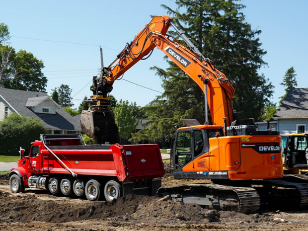 Ashwill Companies' excavator operator dumping dirt in a dump truck on a residential project in Cokato, MN