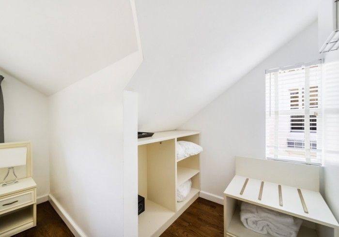 White walk-in closet with shelves, hanging space, and a window over a low bench storage unit.