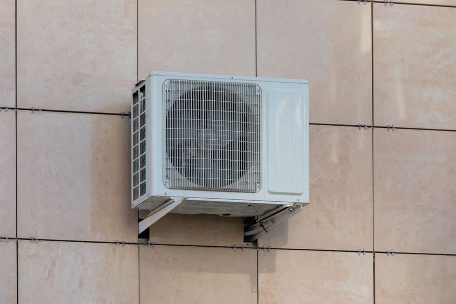 A white air conditioner is mounted on the side of a building.