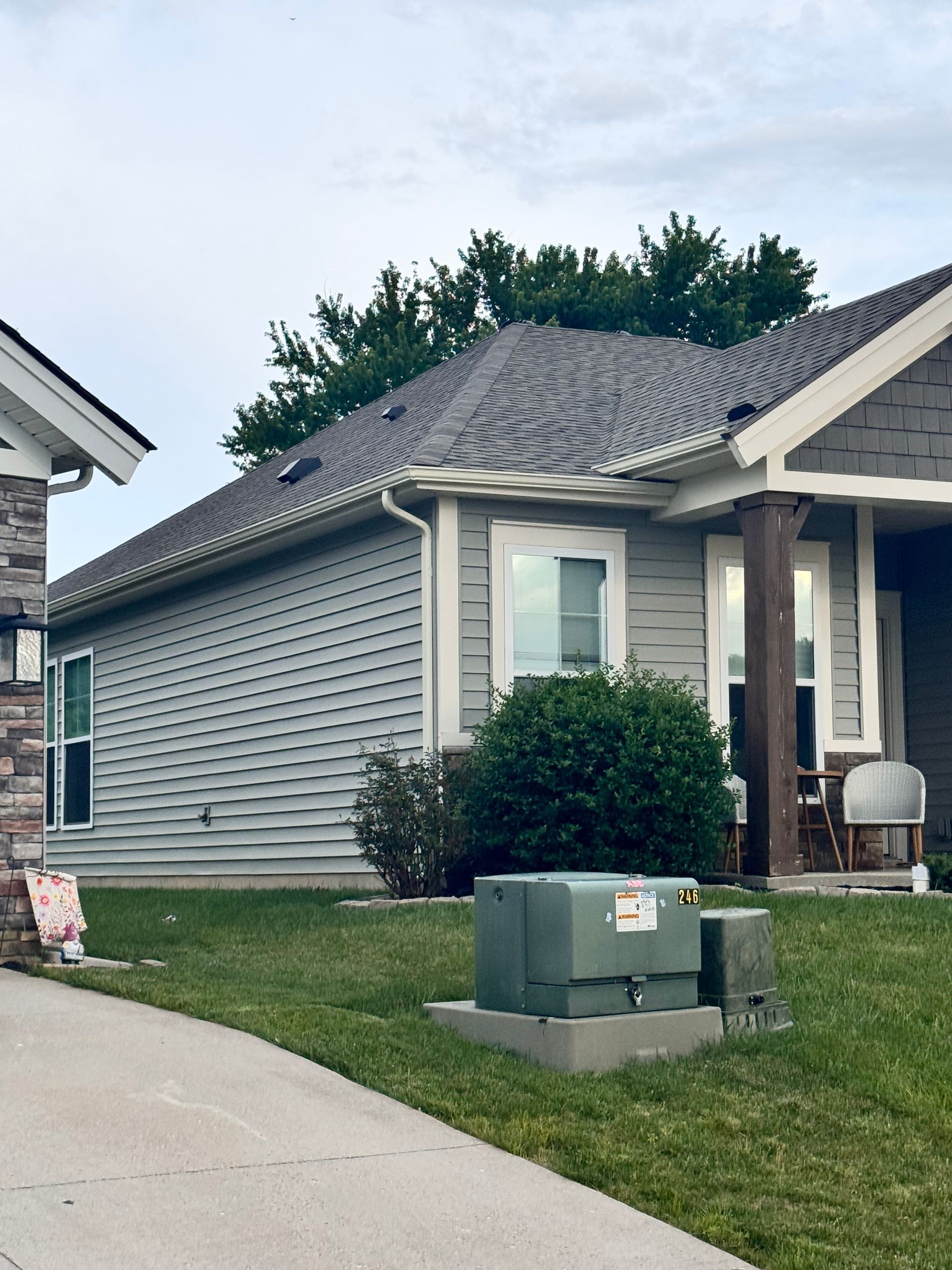 Suburban house with gray siding, driveway, lawn, and green utility boxes in front yard