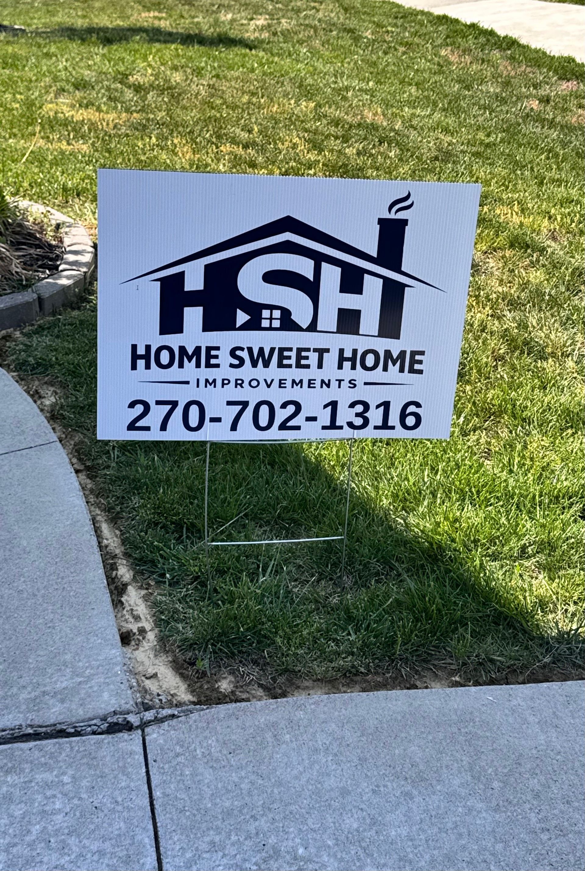 Yard sign reading “HSH Home Sweet Home” with phone number 270-702-1316 on grass by a sidewalk