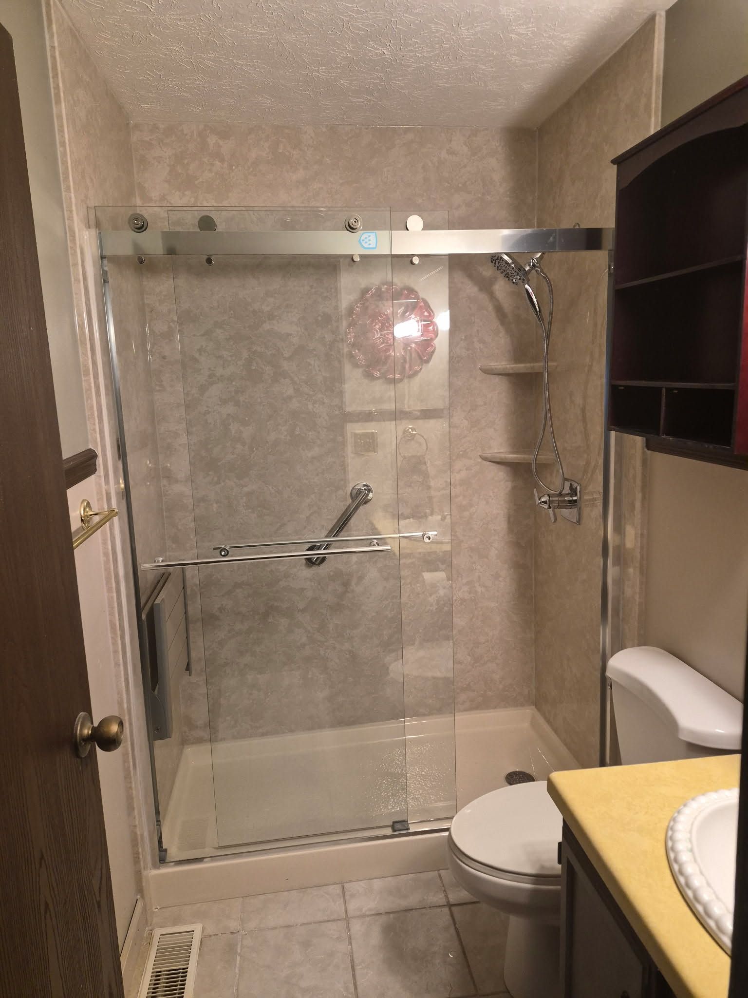 Small bathroom with glass shower enclosure, toilet, and sink vanity.