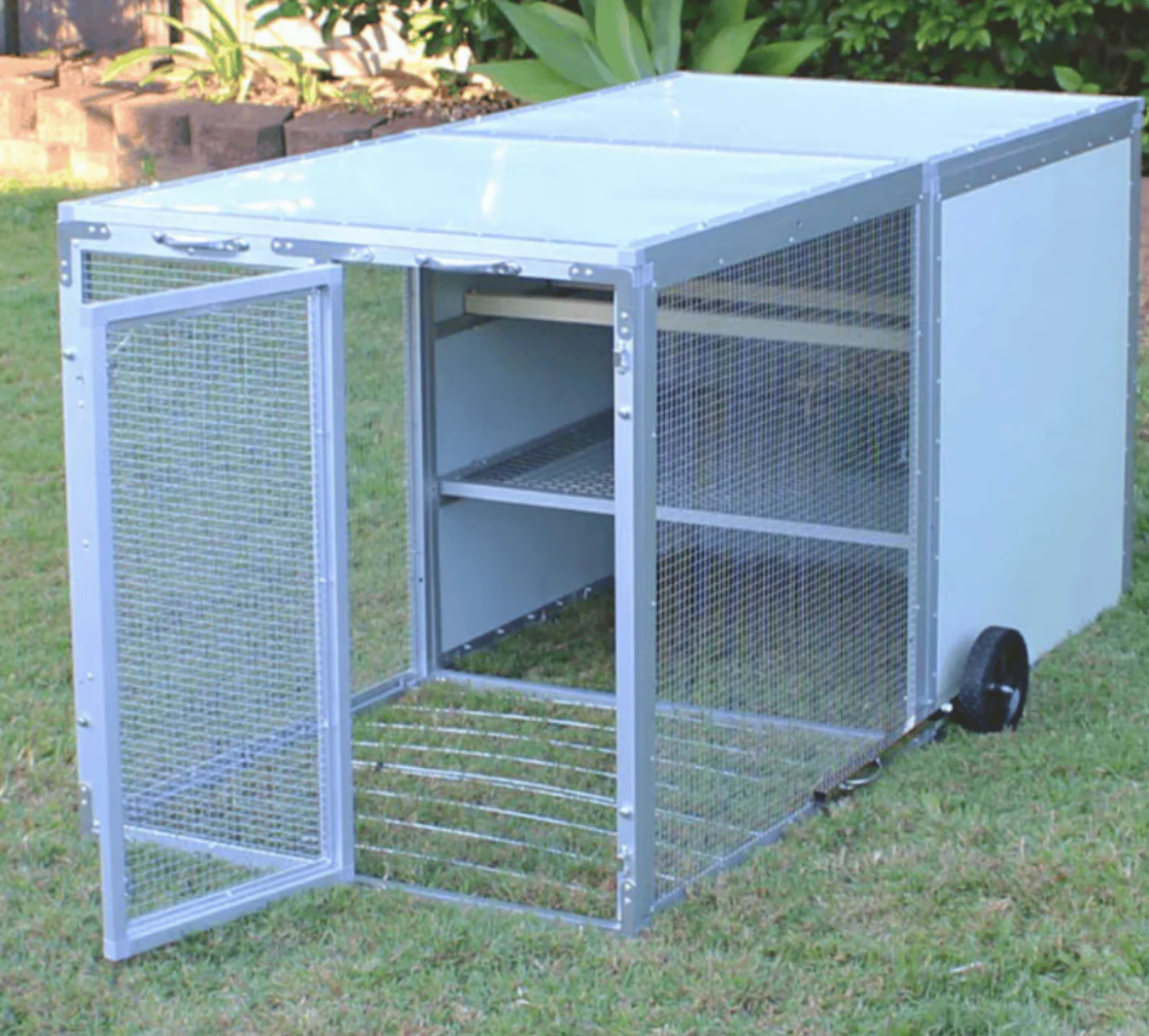 A metal cage with the door open is sitting in the grass