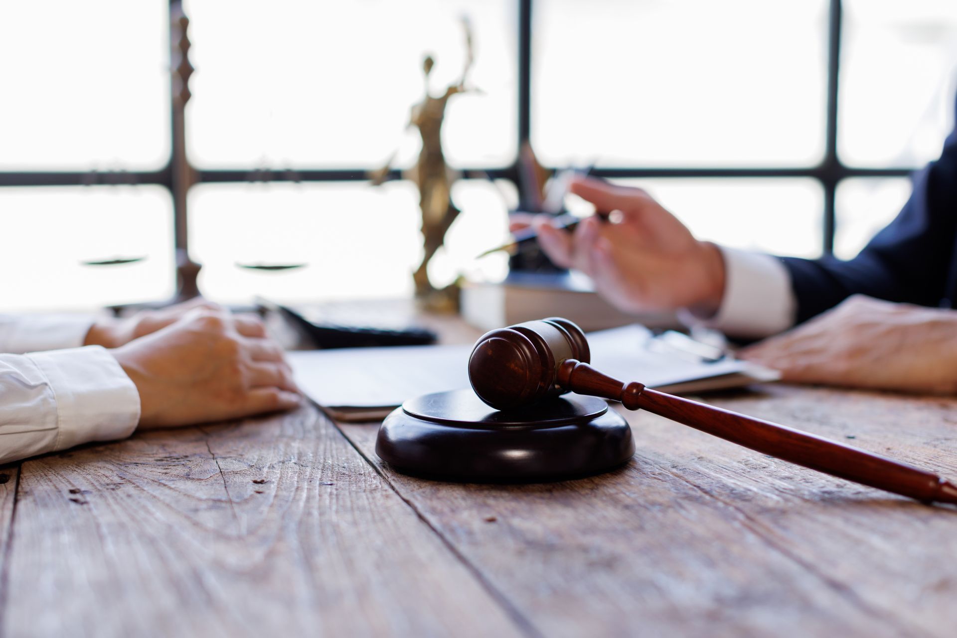Judge’s gavel on a wooden table during a business meeting with people signing documents