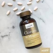 Frasco marrón de suplemento de cloruro de magnesio con tabletas blancas sobre una superficie de mármol claro.