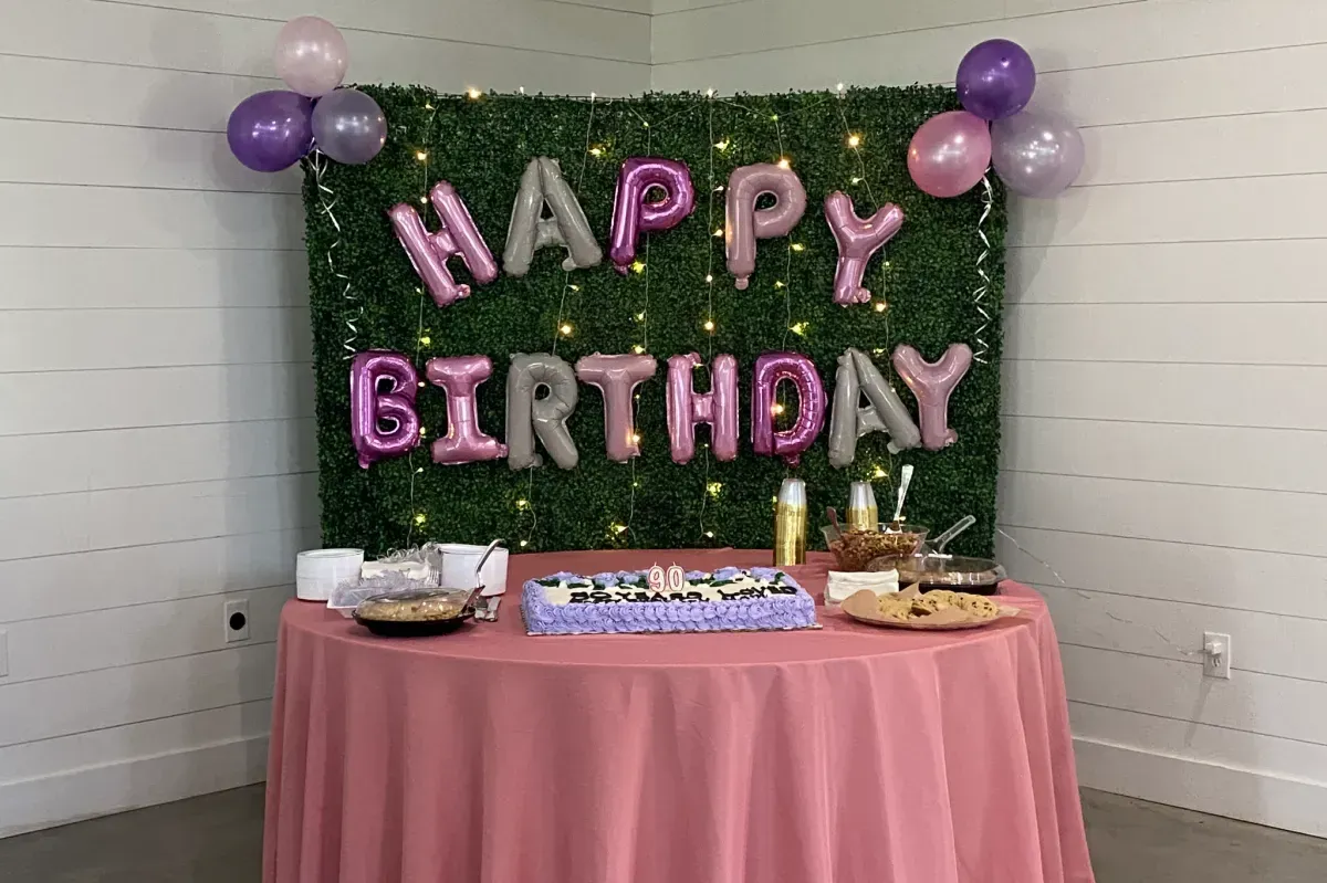A table with a cake and balloons for a birthday party.