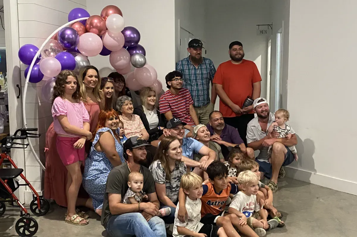 A large group of people are posing for a picture in a room with balloons.