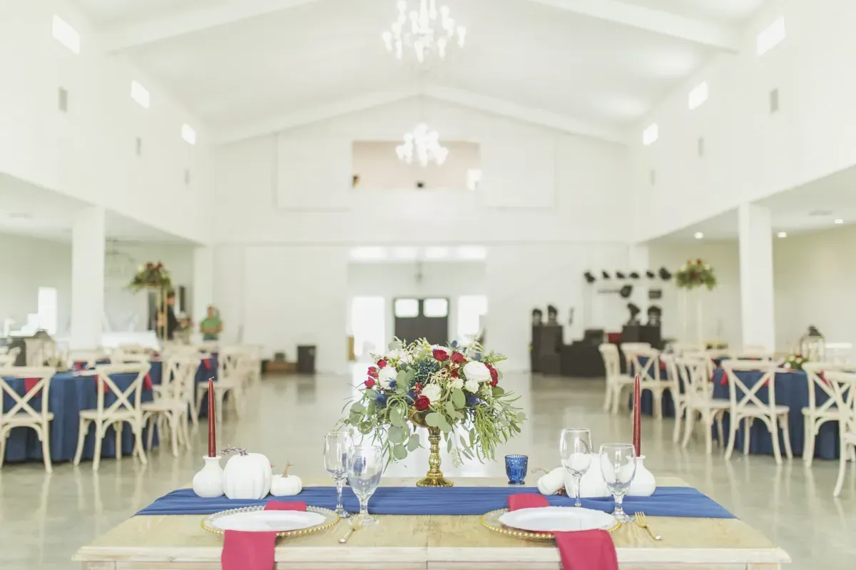 A table set for a wedding reception with a vase of flowers on it.