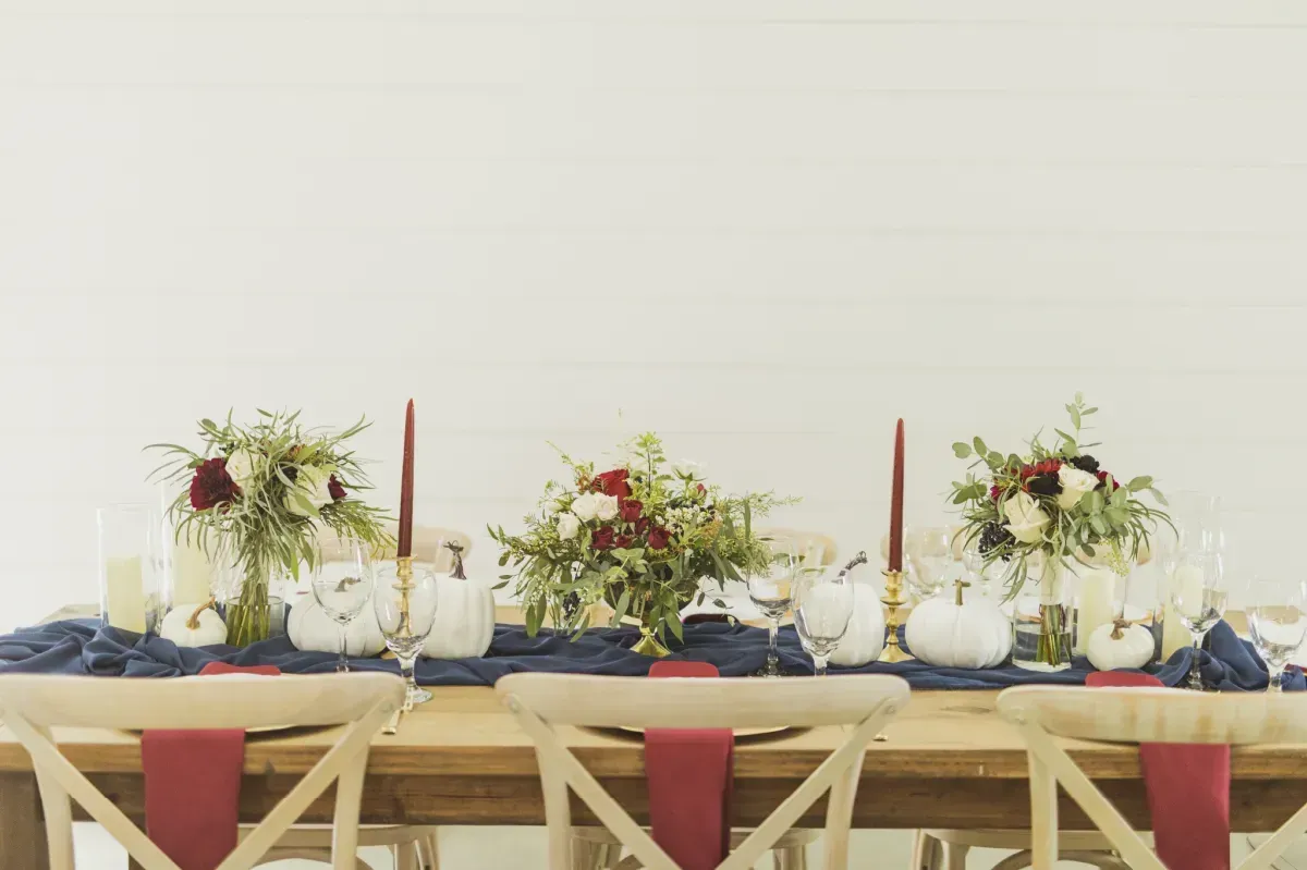 A long wooden table with plates , candles , and flowers on it.