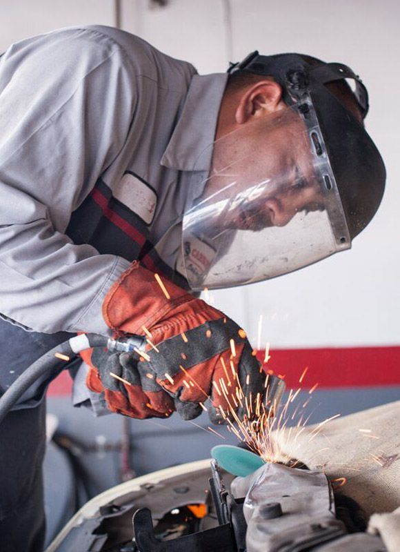 Autobody repair - man using an air powered grinding wheel.