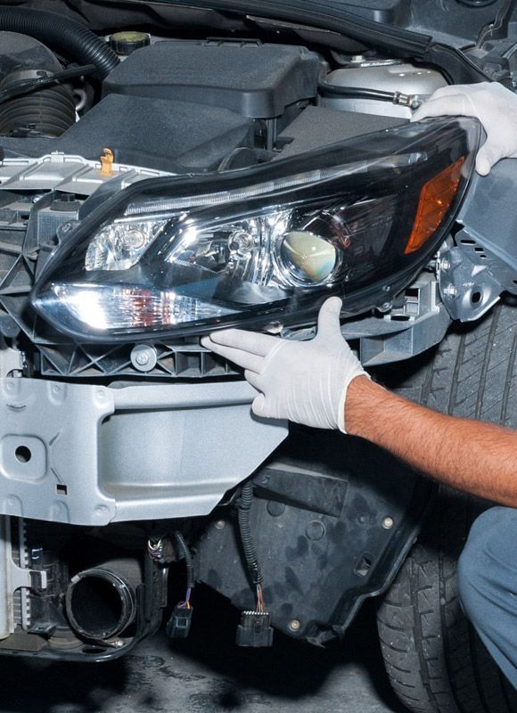 Autobody repair - headlight being replaced by a technician.