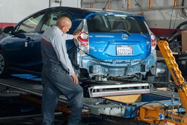 Frame repair and replacement - blue car having it's frame repaired with a frame straightening jig.