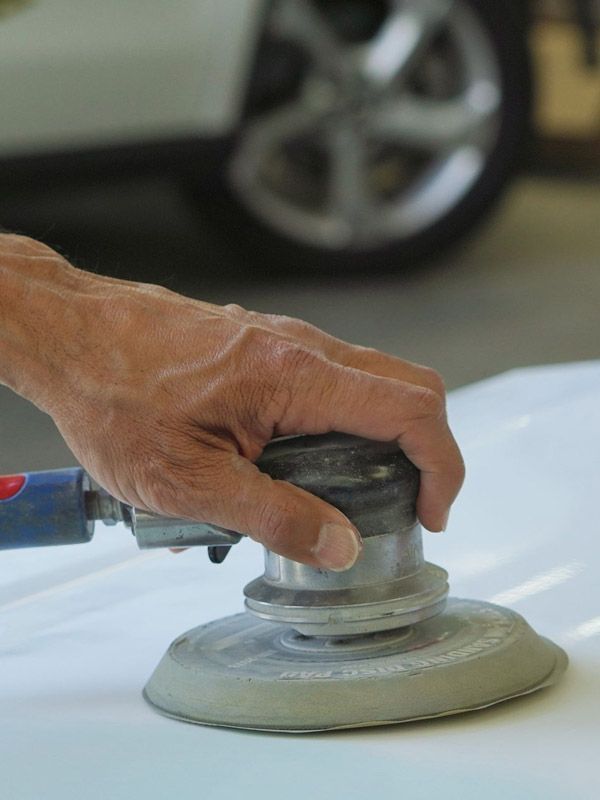 Sanding a repaired car hood. Sanding a repaired car hood.