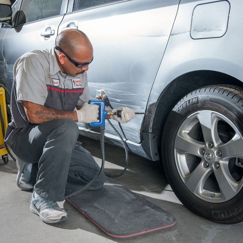Collision repair specialist repairing a dent in a car door.