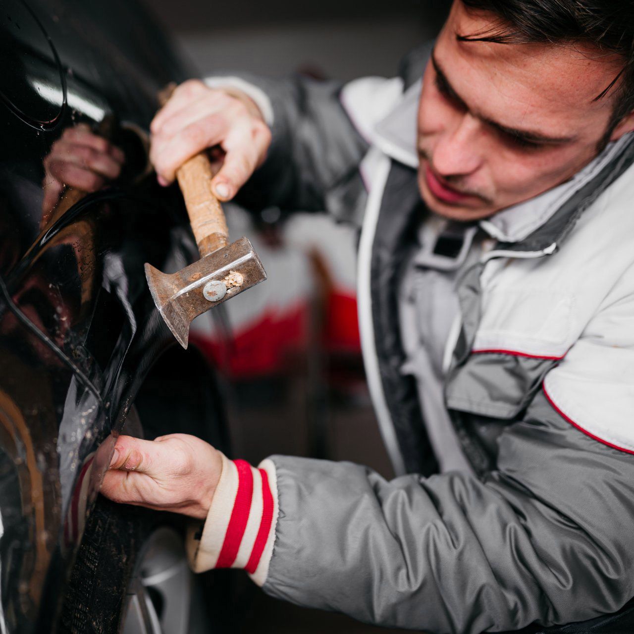 Paintless dent repair being performed by a technician with a small brass hammer.