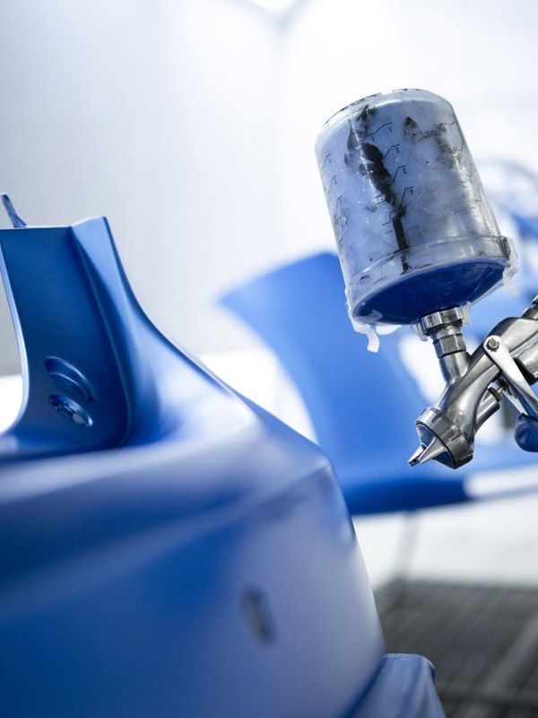 Auto paint professional spraying blue paint on a car fender.