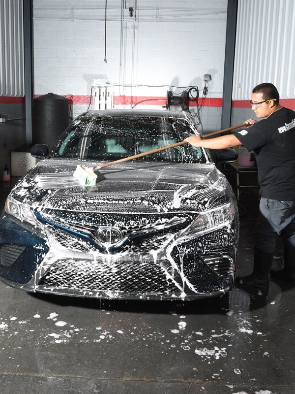 Man washing and detailing a car after having a dent repaired.