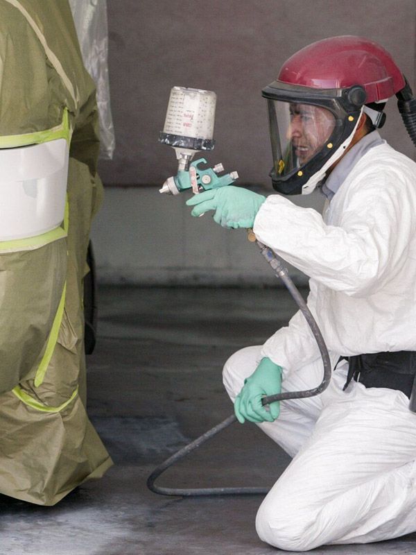 Autobody paint technician spray painting a car door.