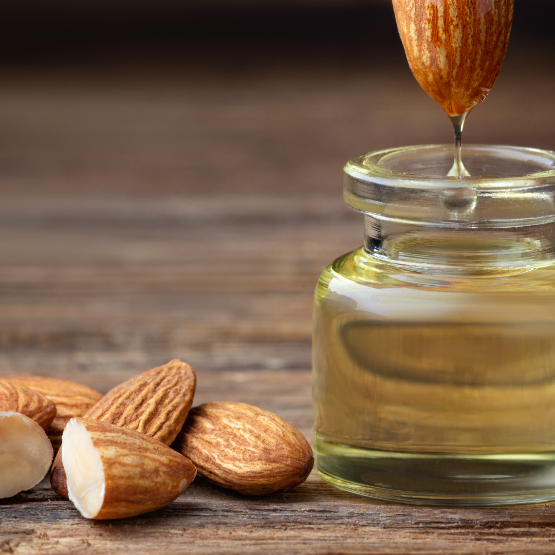 Almonds are being poured into a jar of oil on a wooden table.