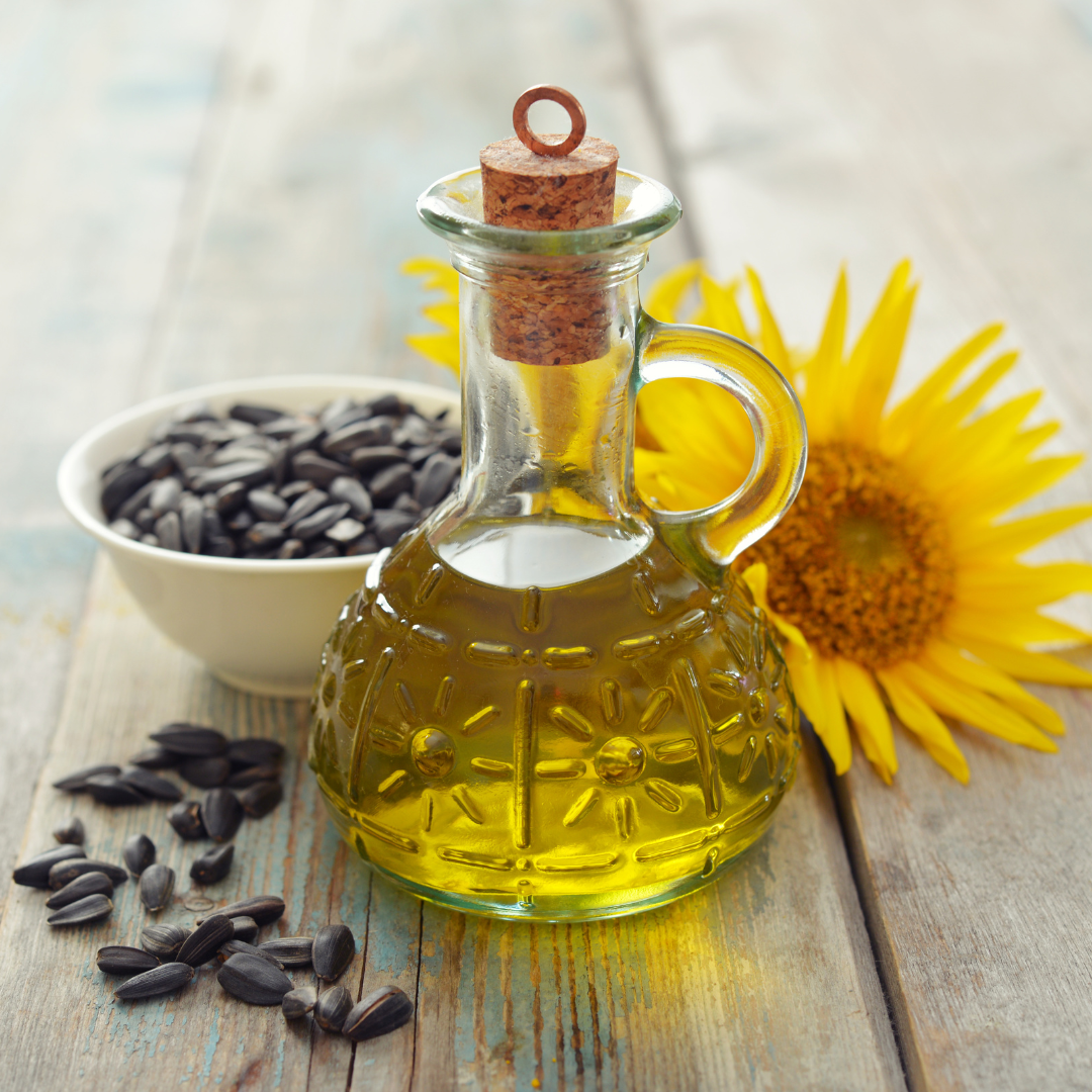 A bottle of oil next to a bowl of sunflower seeds