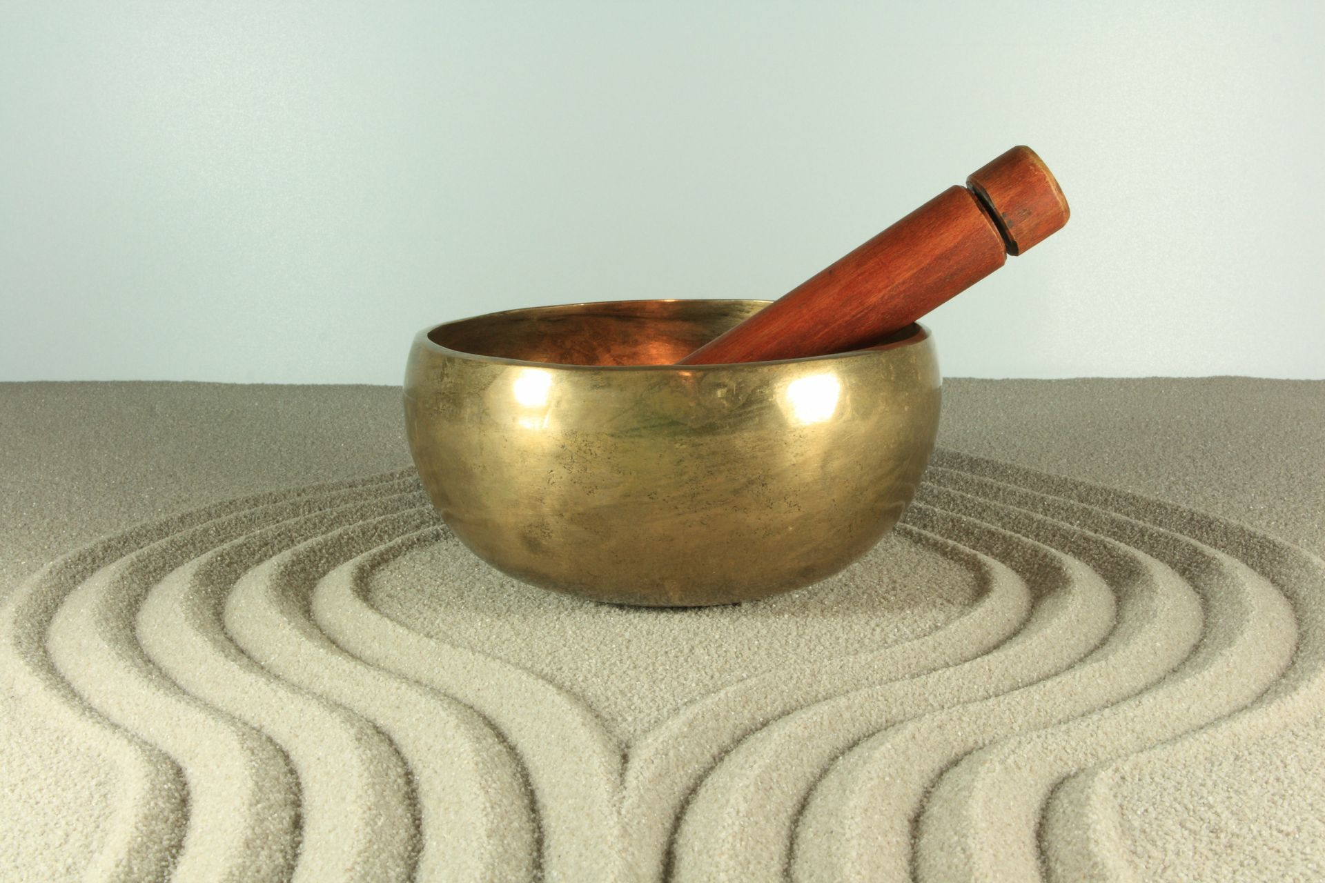 Meditationsschale und Klöppel in einem Zen-Sandgarten