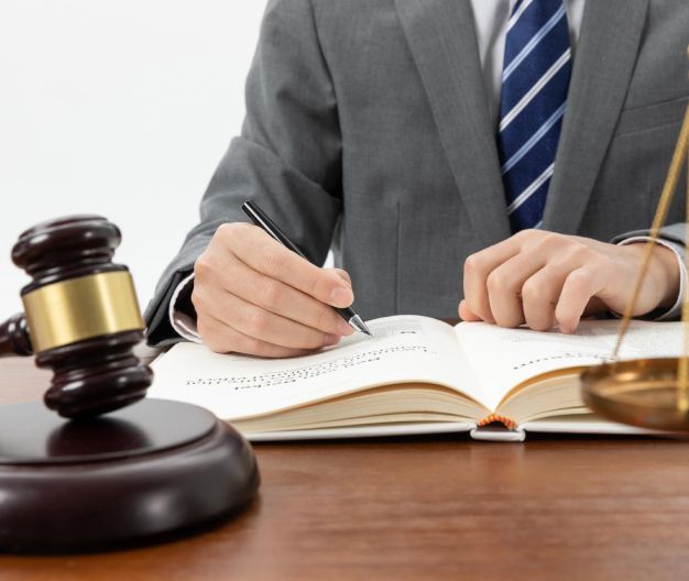 Judge’s gavel beside a suited person writing in an open notebook at a desk